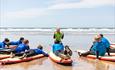 teacher showing kids how to surf on beach