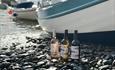 Three bottles of wine on the pebbled beach of Clovelly
