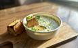 A comforting bowl of soup with croutons, plated on a wooden board
