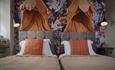 Two beds featuring bright orange and white pillows, arranged to enhance the room's comfort and style.