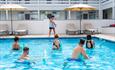 5 people participating in an aqua gym session with pool noodles