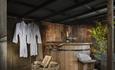 A wooden hot tub with two robes and glasses of champagne.