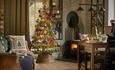 A warm living room scene with a beautifully lit Christmas tree and a table set for holiday gatherings.