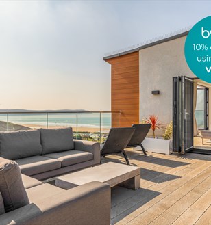 Modern rooftop terrace with ocean view, featuring gray sofas and loungers under clear skies. Text overlay offers a 10% discount with code Visit10.